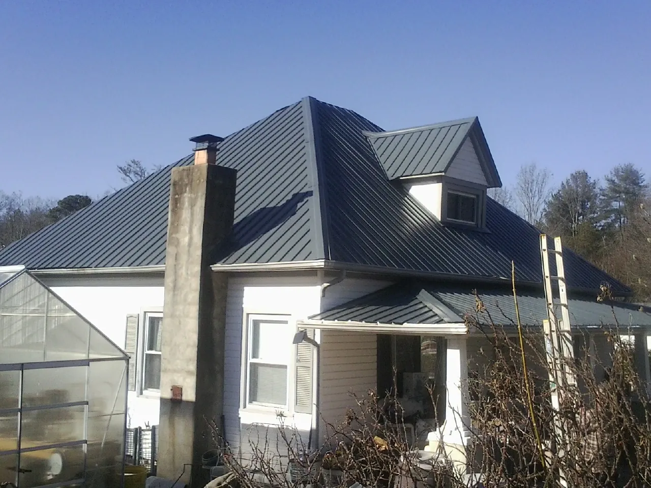 Dark blue standing seam metal roof on a white farmhouse with dormer — Slate & Tile Roof Repair by Roofing Brothers in San Marino