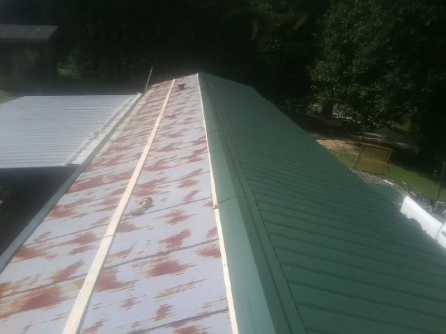 Old rusted panels beside newly installed green metal roofing — Wind Damage Roof Repair by Roofing Brothers in San Marino