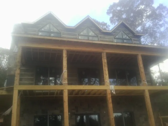 Dormers and porch framing on a large log home under construction — Roof Coating work by our crew in San Marino