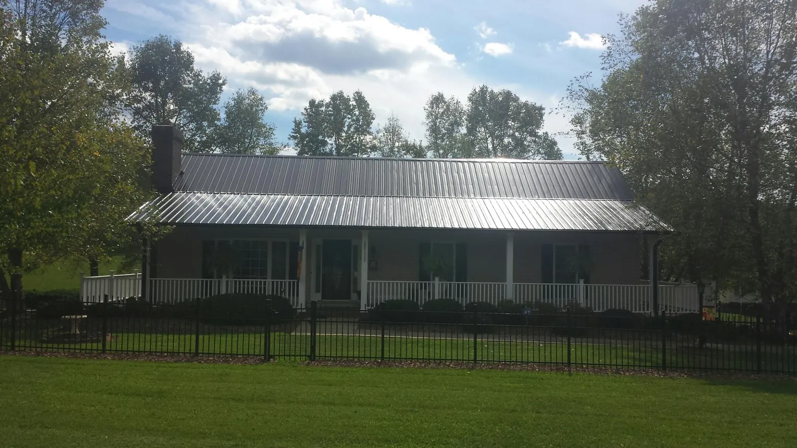Gray metal roof on a brick ranch with a full width front porch — Gutter Guard Installation work by our crew in San Marino