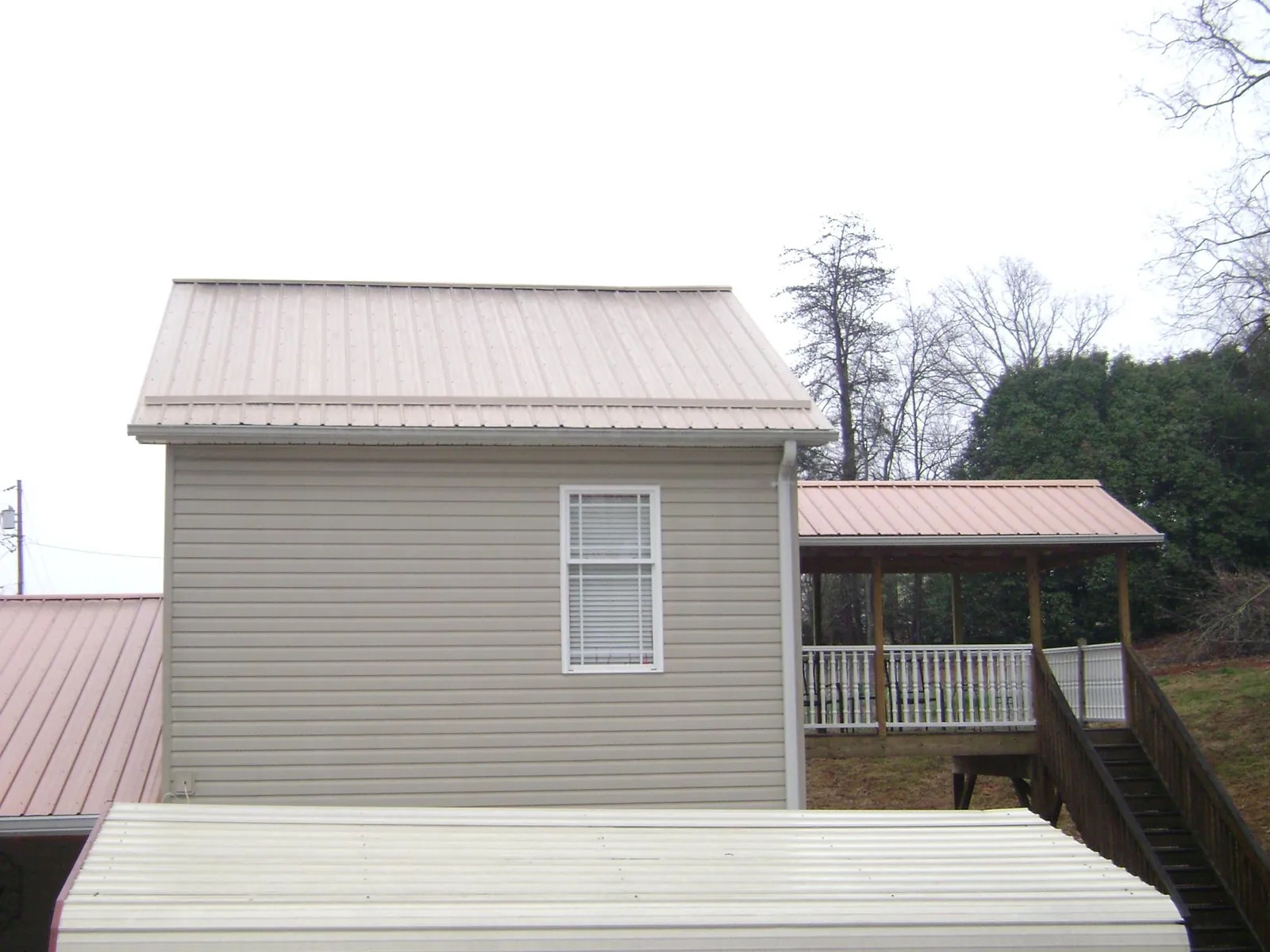 Tan metal roofs on a two story addition and attached porch, from a Roof Replacement job in San Marino
