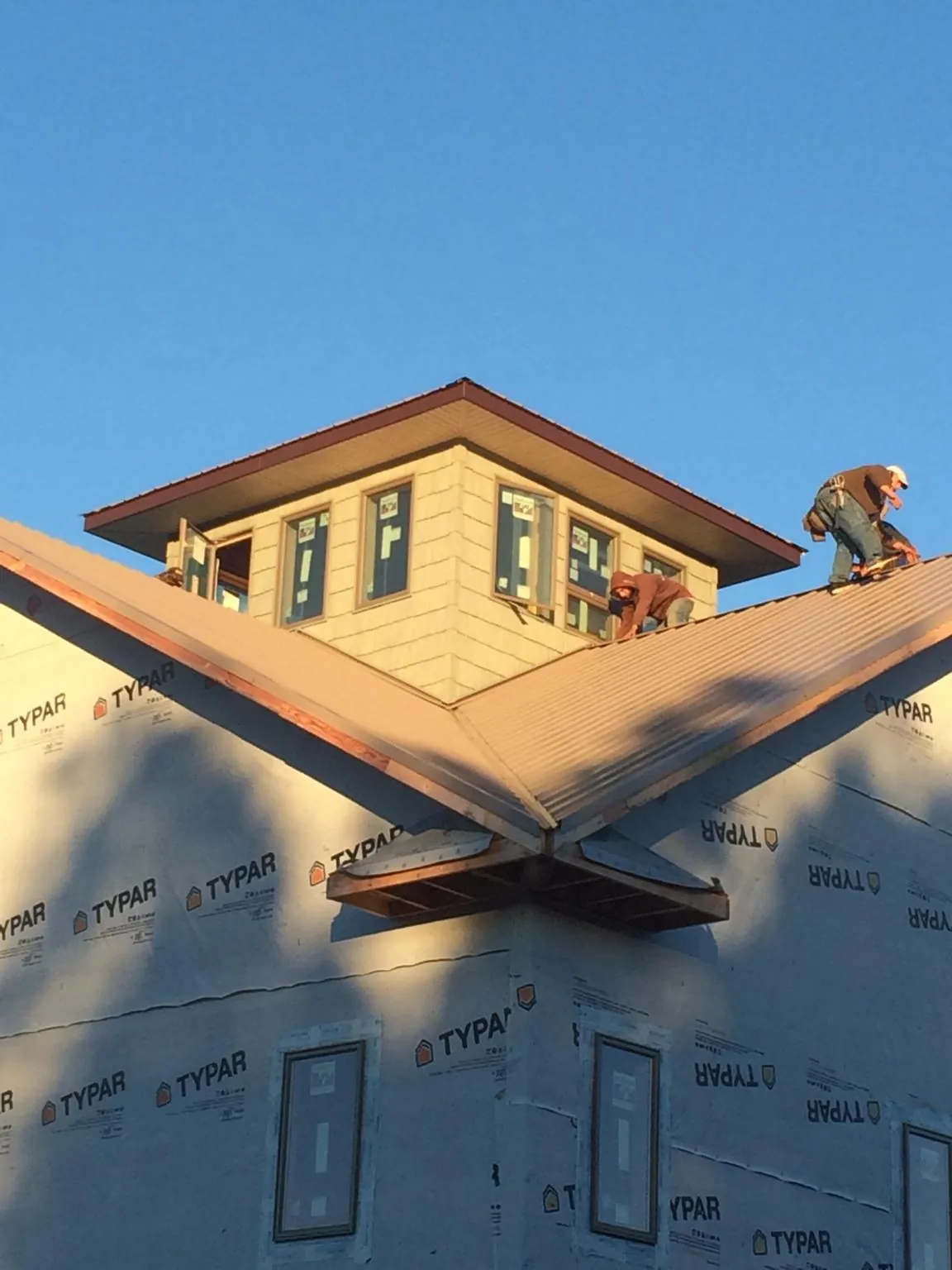 Roofers working around a rooftop cupola on a new metal roof at sunset — Roof Waterproofing in San Marino by Roofing Brothers